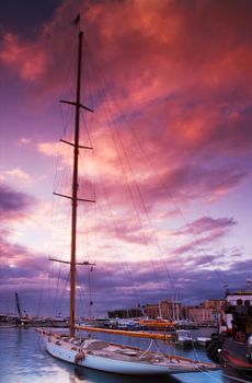Image shows a moored sailing boat under a dramatic sunset sky. Pictured captured in Cannes, France