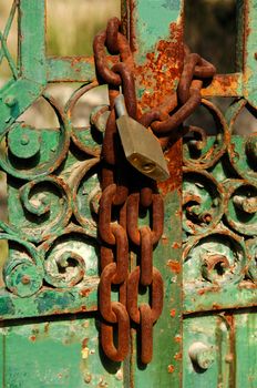 Rusty chain and padlock on an heavily weathered house gate