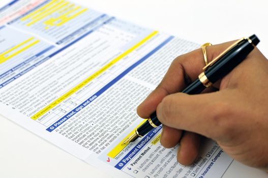 Man signing life insurance application form using a fountain pen