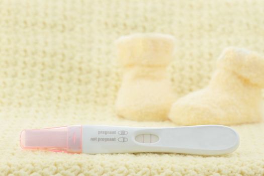 Positive pregnancy test with little cute baby booties in the background.