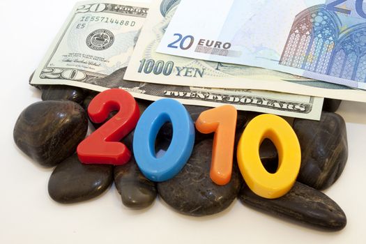 Intertwined, difficult nature of the global economy is reflected in the images of euro, yen, and dollars on the rocks accented by colorful numbers, 2010;