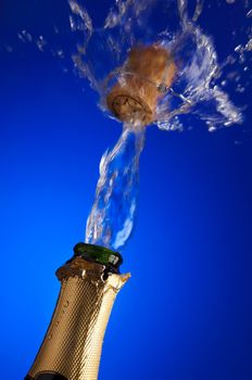 clos-up of an uncorked champagne bottle with cork flying away on the liquid