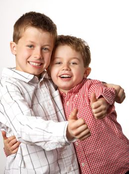 two cute young boys arm in arm with thumbs up