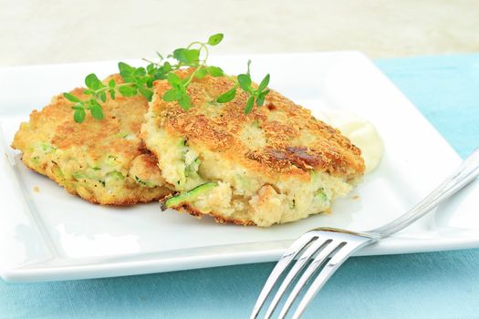 Healthy vegetarian Zucchini "Crab Cakes" served with horseradish sauce and a sprig of thyme.