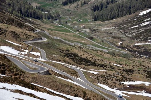 Mountain pass road through snow covered rocks on Spluegen Pass in Switzerland, Europe
