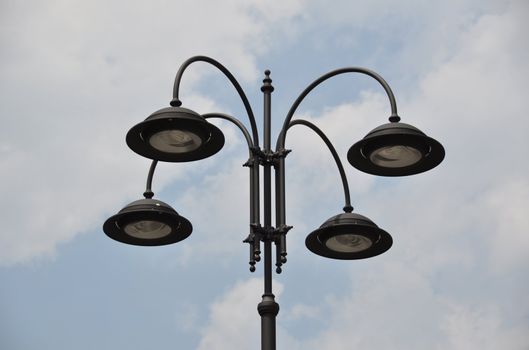 Closeup of an old fashioned street lamp in front of bright and cloudy sky