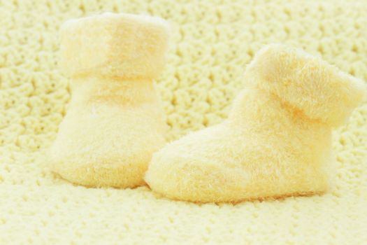 Yellow baby booties and blanket with room for text.