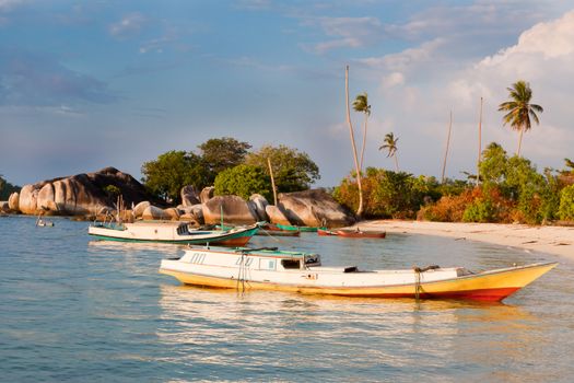 Indonesian fishing boat in small harbor, blue sky and palm trees in background