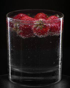 Cocktail with strawberries isolated on black.