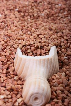 Buckwheat groats with a wooden deep spoon for packaging.