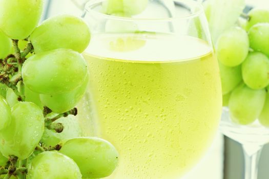White grape juice in wine glasses with fresh grapes. 