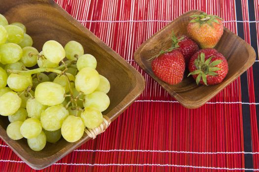 strawberries and grapes in a wooden tray
