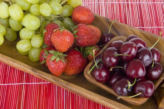 summerfruit in a wooden tray on a red carpet