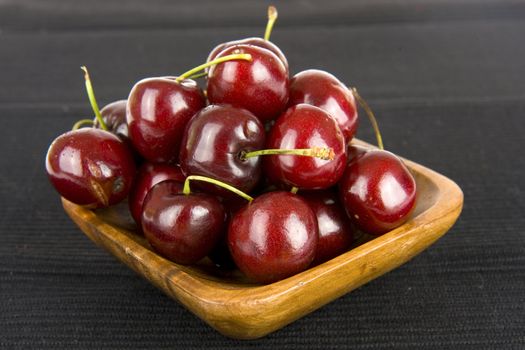 cherries in a wooden tray on black