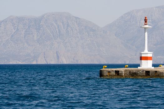 Lighthouse in rocky bay on the island background