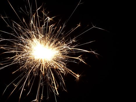 Details of a burning handheld firework over black background