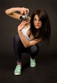 Young girl posing with retro camera isolated on black background