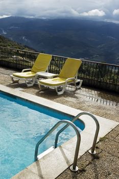 Long chairs by the pool in a mountain landscape