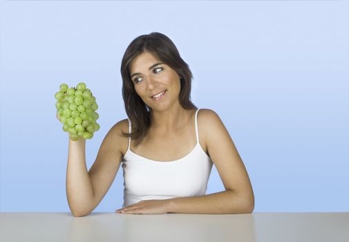 Beautiful young woman holding and looking to the grapes