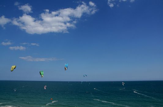 panorama of people doing kitesurf sport on holiday at a beach
