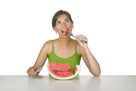 Beautiful young woman in the kitchen eating a watermelon slice