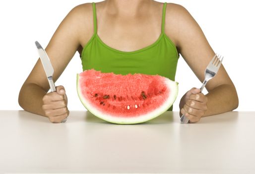 Beautiful young woman in the kitchen eating a watermelon slice