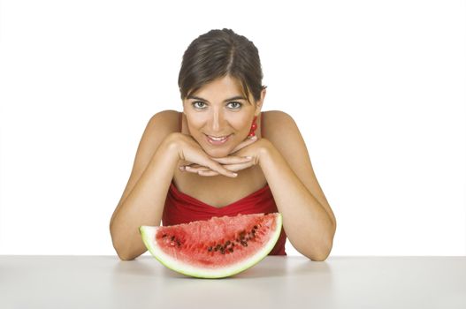 Beautiful young woman in the kitchen with a watemelon slice in front of her