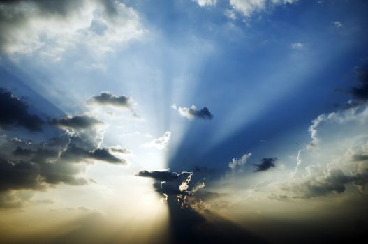 Sunburst in blue sky with beams shining through the clouds. 