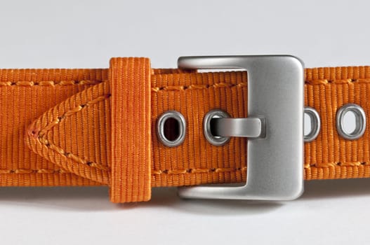 Closeup of an orange watchstrap with metal buckle