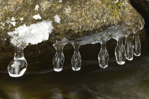 Hanging icecles form a rock over a river