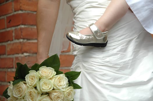 Bride holding her child and flowers.