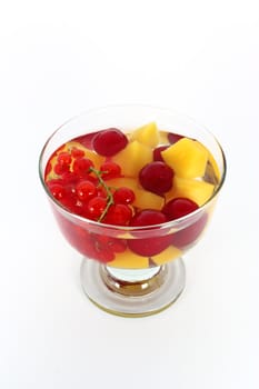 Peach compote with fresh red currants and sour cherries in glass bowl isolated on white