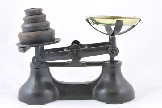 Antique weighing scales with brass bowl and rusty black weights.