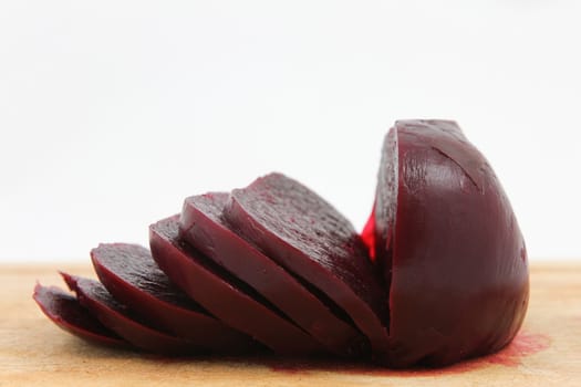 Cooked beetroot sliced on chopping board against a white background.