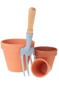 Steel rake on white background near to ceramic pots.