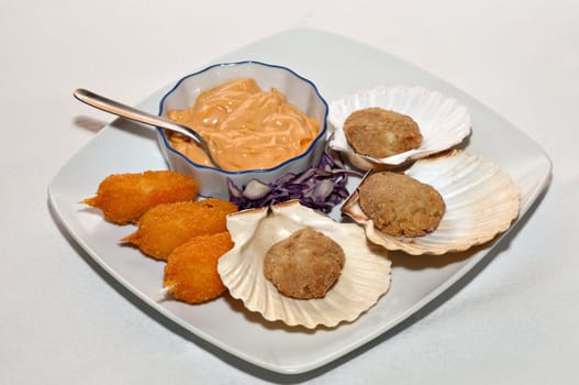 a dish of fried crab claws and fish meatballs with pink sauce