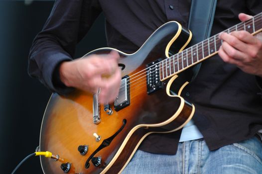 Man playing his guitar. Note his hand is in motion.