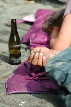 Homeless man is holding out his hand while sleeping.