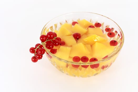 Peach compote with fresh red currants in glass bowl isolated on white