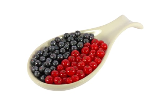 Blueberries and currants in a spoon isolated on white
