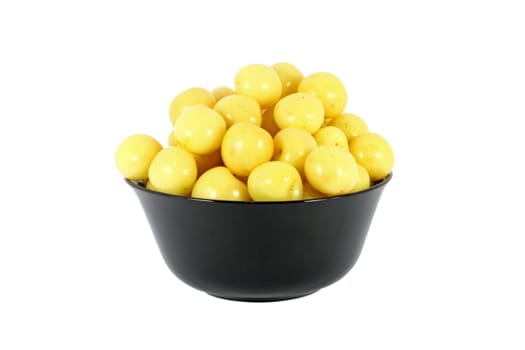 Black bowl full of yellow cherries isolated on white