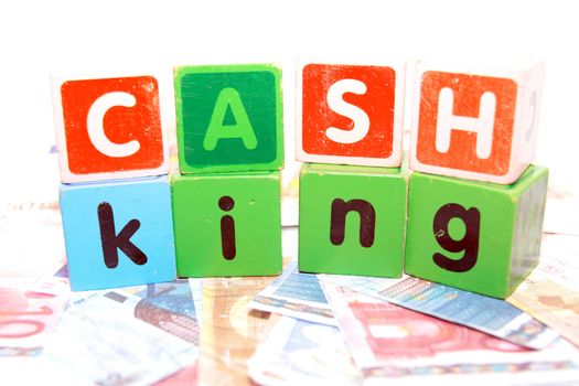assorted childrens toy letter building blocks against a white background on money that spell cash king