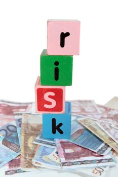 assorted childrens toy letter building blocks against a white background on money that spell risk