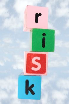 assorted childrens toy letter building blocks against a cloud background that spell risk with clipping path