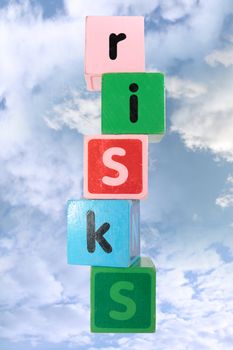 assorted childrens toy letter building blocks against a cloud background that spell risks with clipping path