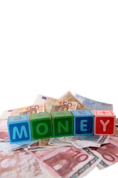 assorted childrens toy letter building blocks against a white background on money that spell money with copy space