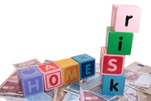 assorted childrens toy letter building blocks against a white background on money that spell home risk