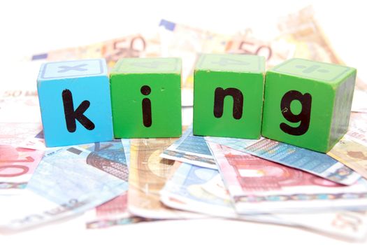 assorted childrens toy letter building blocks against a white background on money that spell king