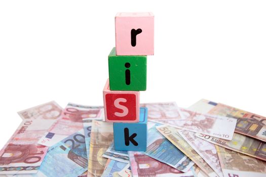 assorted childrens toy letter building blocks against a white background on money that spell risk