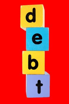 assorted childrens toy letter building blocks against a red background that spell debt with clipping path